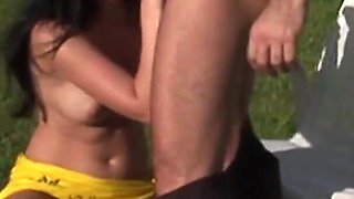 A very sensual girl fucks a male near the sea on the lawn