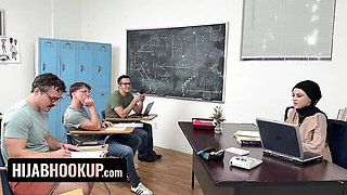 Ruby Moon in black hijab and polka-dot blouse sits at classroom desk with laptop